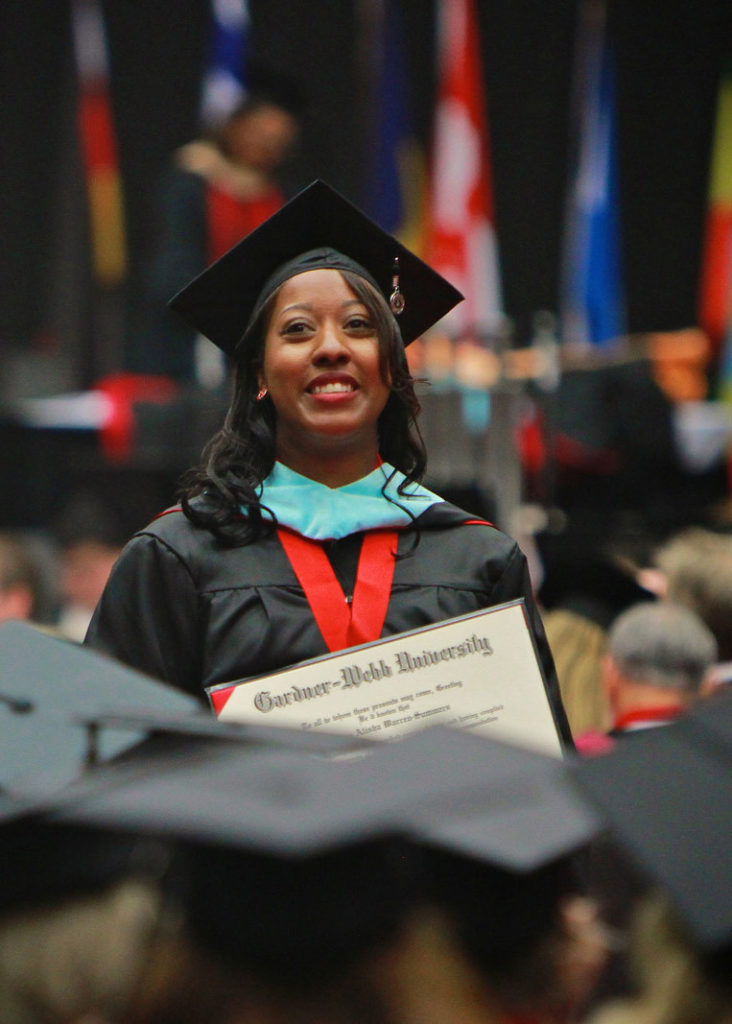 A student proudly displays her diploma during the graduation ceremony