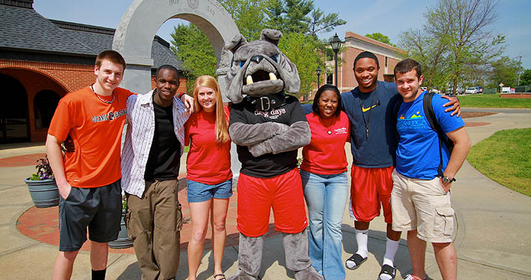 GWU students standing in front of arch on campus with mascot